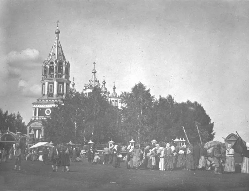 Чёрно-белая дореволюционная фотография: пятиглавый кирпичный храм с высокой шатровой колокольней, у стен — толпа с хоругвями