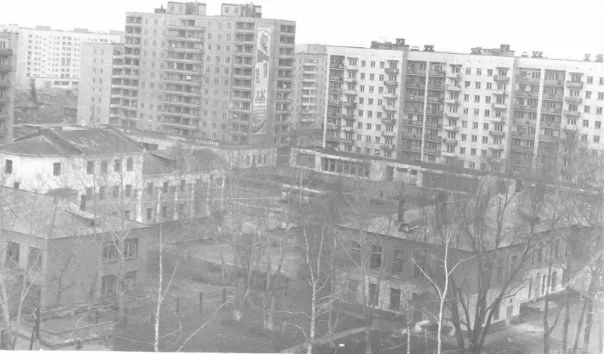 Чёрно-белый снимок приземистого кирпичного здания без глав и колокольни на фоне новостроек