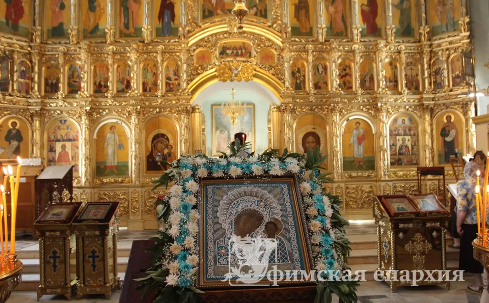 Икона в киоте с цветами перед иконостасом